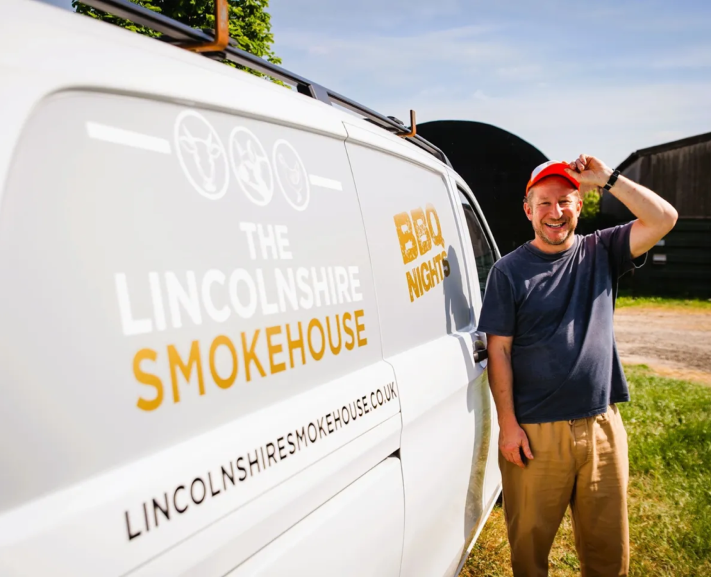 Man in cap beside smokehouse van