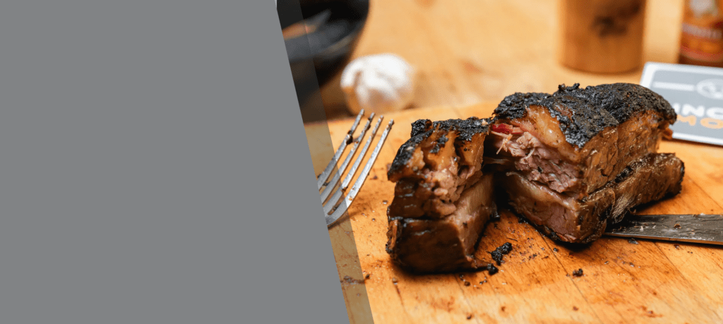 Grilled steak with a fork on a wooden cutting board.